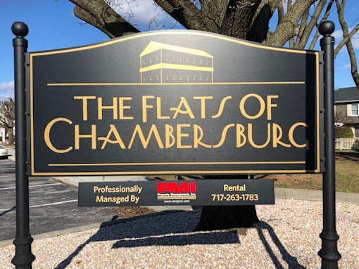 A sign for The Flats of Chambersburg, professionally managed by a company with a phone number provided.