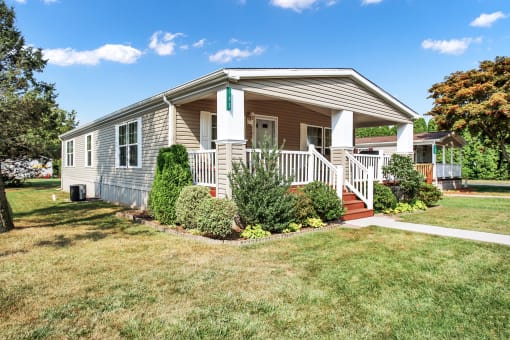 a small house with a porch and a lawn in front of it