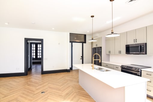 a white kitchen with a large island and a sink