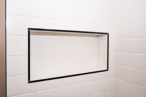 a white tiled bathroom with a mirror in the shower