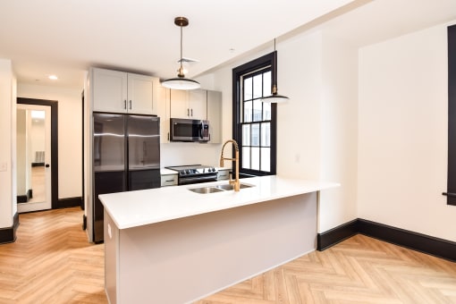 a kitchen with a white counter top and a stainless steel refrigerator