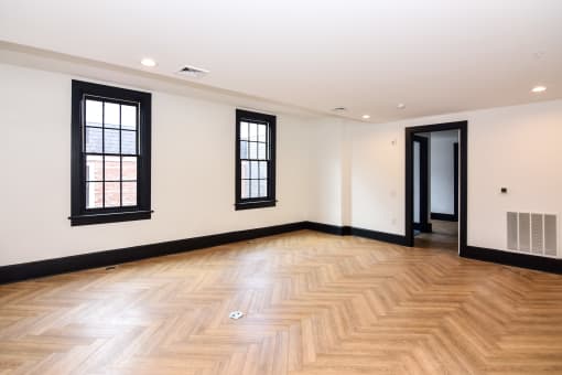 the living room and hallway of a new home with wood flooring and windows