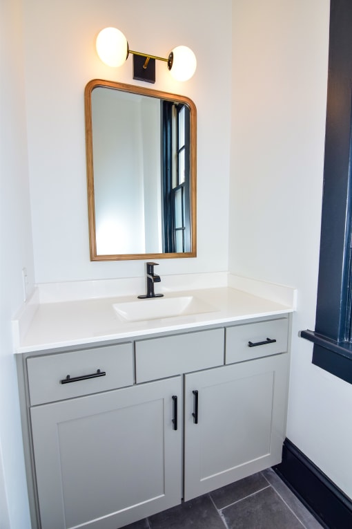 a bathroom with white cabinets and a sink and a mirror