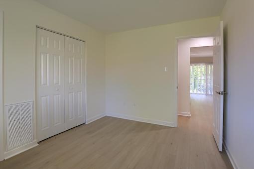 A room with a white door and wooden floor.