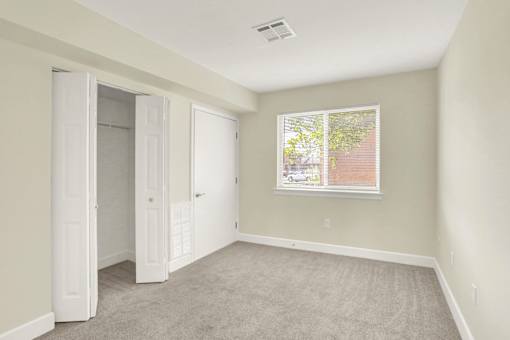 A room with a carpeted floor and a window showing a view of a street.