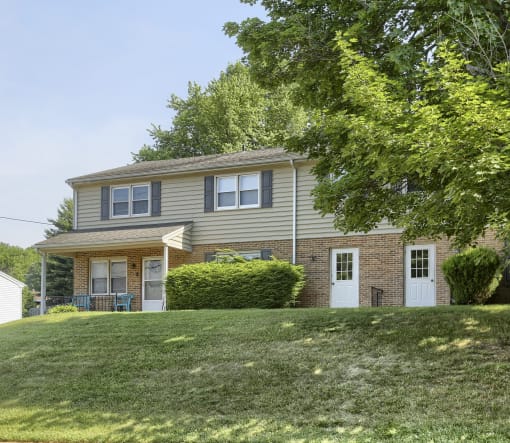 the front of a house with a lawn and a tree