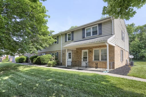 the front of a house with a lawn and trees