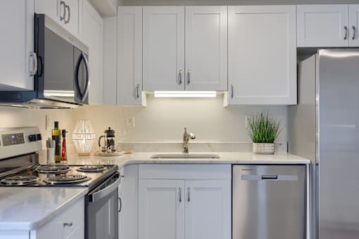 A modern kitchen with white cabinets and stainless steel appliances.