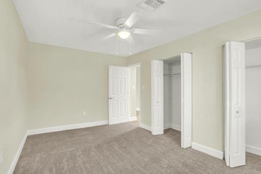 A room with a ceiling fan and carpeted floor.