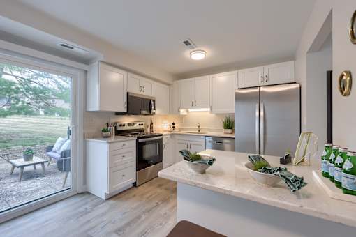 A kitchen with a white counter top and stainless steel appliances.