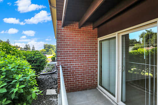 A red brick wall with a glass door and a white railing.