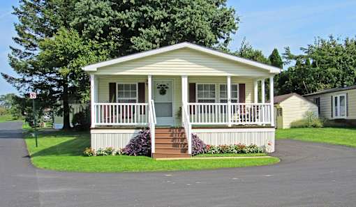 A small white house with a porch and a red door.