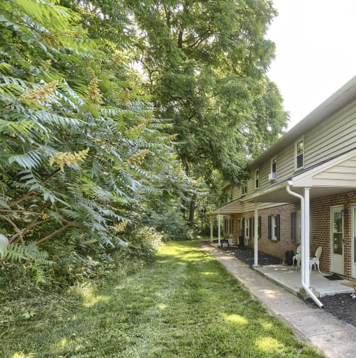 the side of a house with a yard and trees