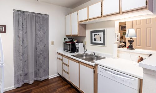 A kitchen with white cabinets and a grey curtain.