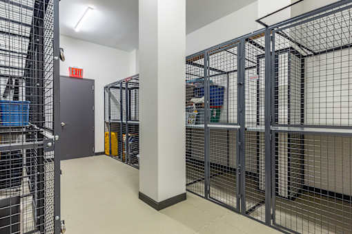 A long hallway with a metal gate on the left and a red exit sign above it.