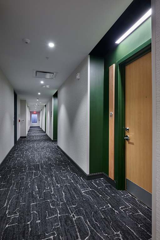 a long corridor with wooden doors and white walls
