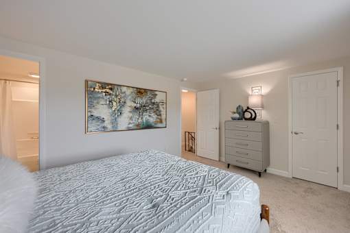 A bedroom with a large bed and a painting on the wall.