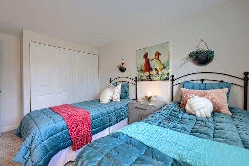 A bedroom with two beds and a painting on the wall.