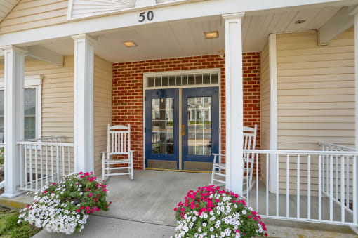 the front porch of a house with two rocking chairs and a blue door