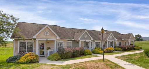 a home with a porch and a street light in front of a grassy field