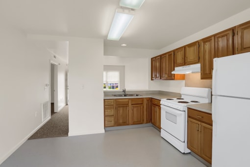 an empty kitchen with white appliances and wooden cabinets