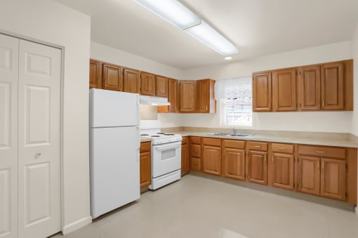 an empty kitchen with white appliances and wooden cabinets