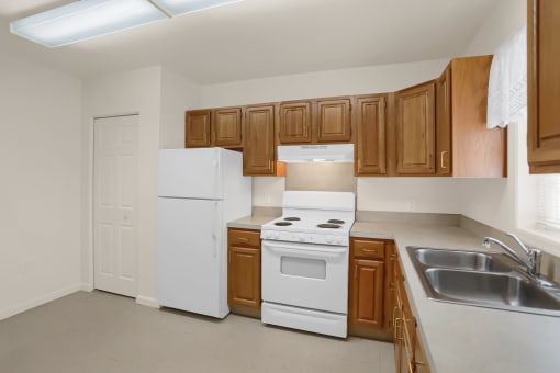 an empty kitchen with white appliances and wooden cabinets