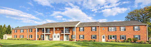 A large red brick building with a green lawn in front.