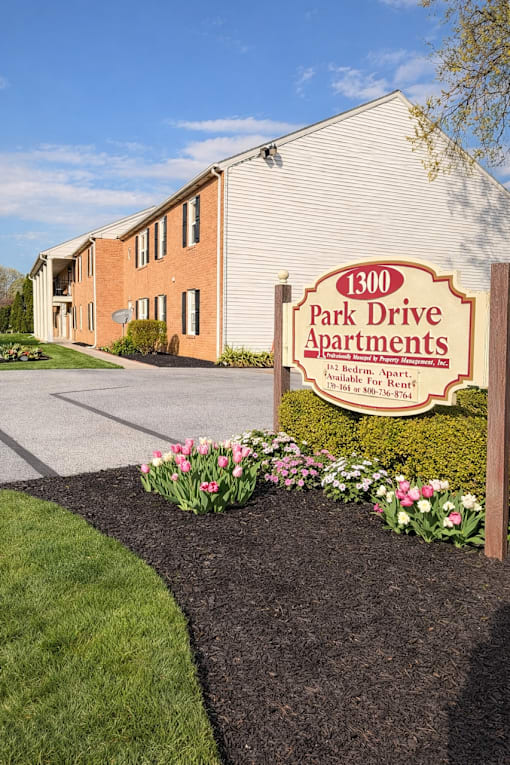A sign for 1300 Park Drive Apartments sits in front of a brick building.