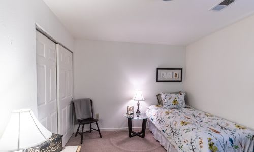 A bedroom with a bed, chair, and two lamps.