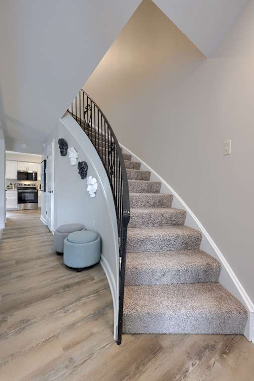 A staircase with a grey carpeted runner and a black metal railing.