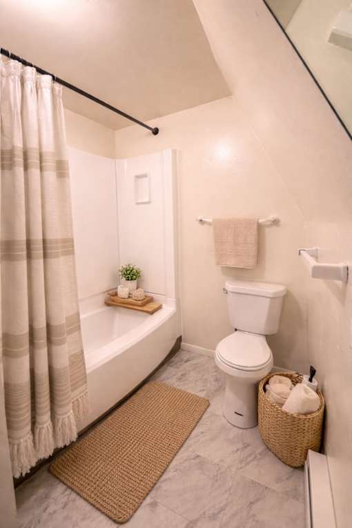 A white toilet sits next to a bathtub in a bathroom.