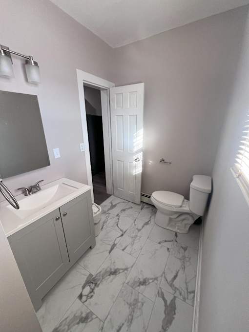 A bathroom with a sink, toilet and a mirror.