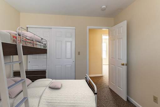 A bedroom with a bunk bed and a carpeted floor.
