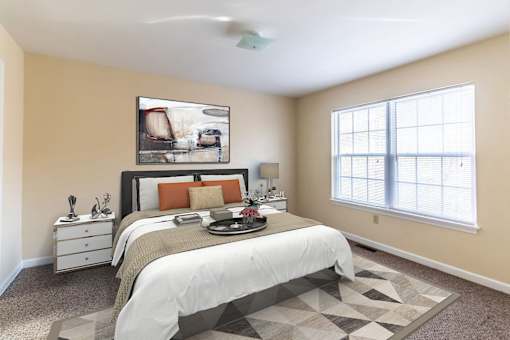 A bedroom with a bed, nightstand, and a painting on the wall.
