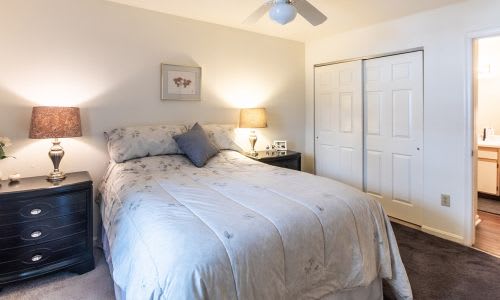 A bedroom with a bed, nightstand, and a ceiling fan.