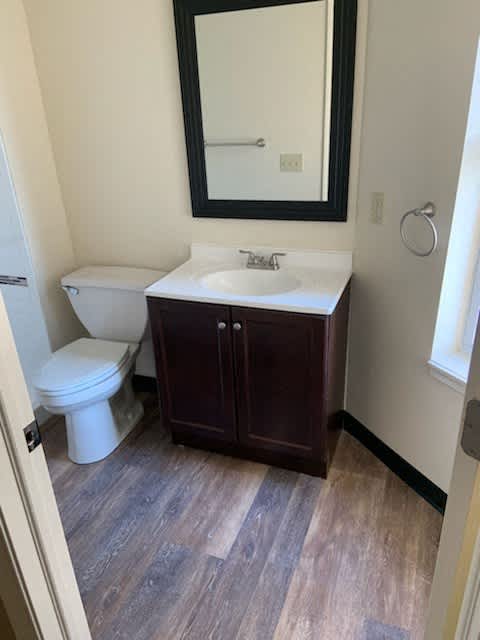 A bathroom with a toilet, sink, and mirror.