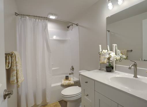 A white bathroom with a toilet, sink, and shower.