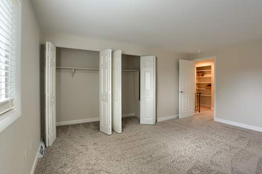 A room with a carpeted floor and a closet with white doors.