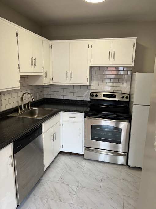 an empty kitchen with white cabinets and stainless steel appliances