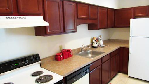 A kitchen with a white stove and brown cabinets.