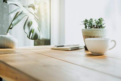 a wooden table with a coffee cup and a plant