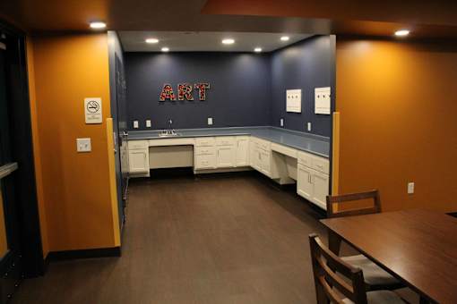 A room with a brown floor and a black wall with the word ART on it.