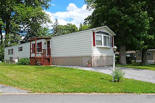 A mobile home with a red door and a deck.