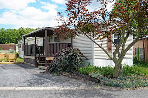 A house with a porch and a tree in front.