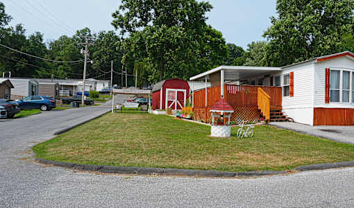 A red and white house with a porch and a white lawn chair.