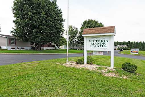 A sign for Victoria Manor Estates stands in a grassy area.