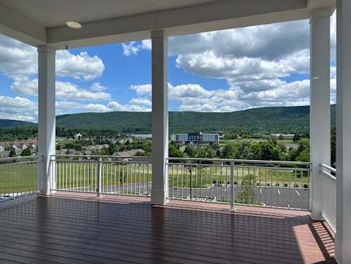 A porch with a view of a town and mountains.