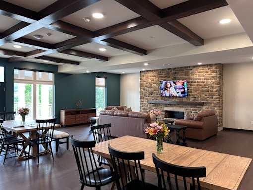 A living room with a stone fireplace and a television mounted above it.