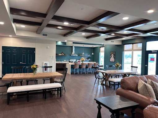 A large room with tables and chairs and a long wooden table in the center.